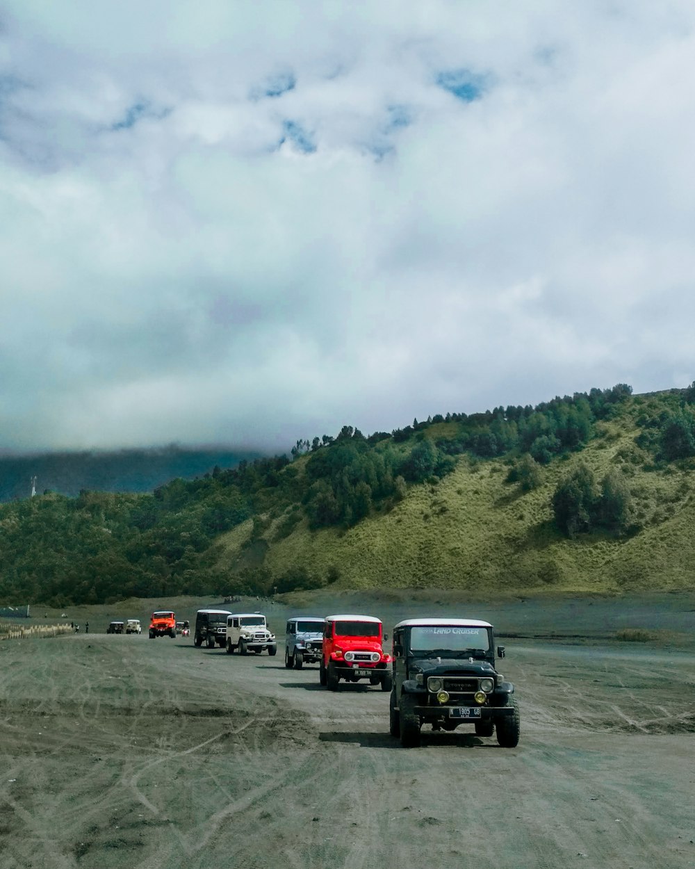 a line of trucks driving down a dirt road