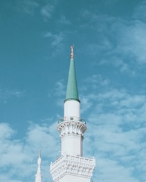 a white building with a green steeple against a blue sky