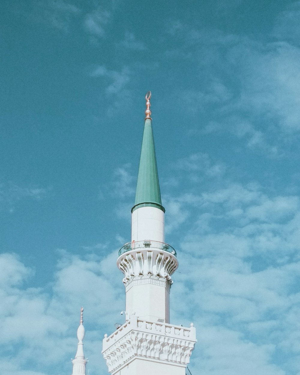 a white building with a green steeple against a blue sky