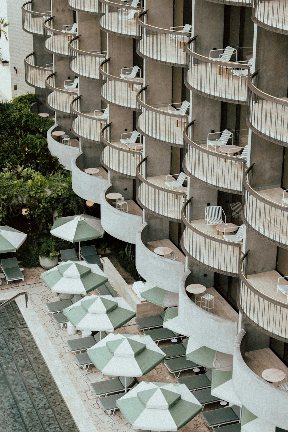 an aerial view of a hotel pool with lounge chairs and umbrellas