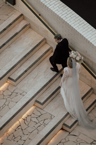 a bride and groom walking down the stairs of a building