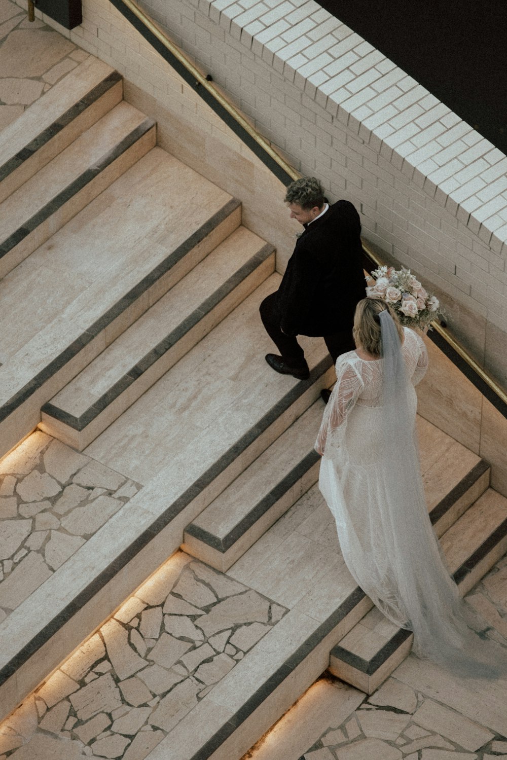 a bride and groom walking down the stairs of a building