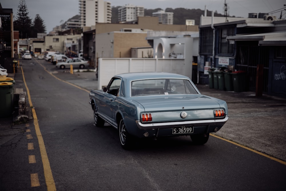 a blue car driving down a street next to tall buildings