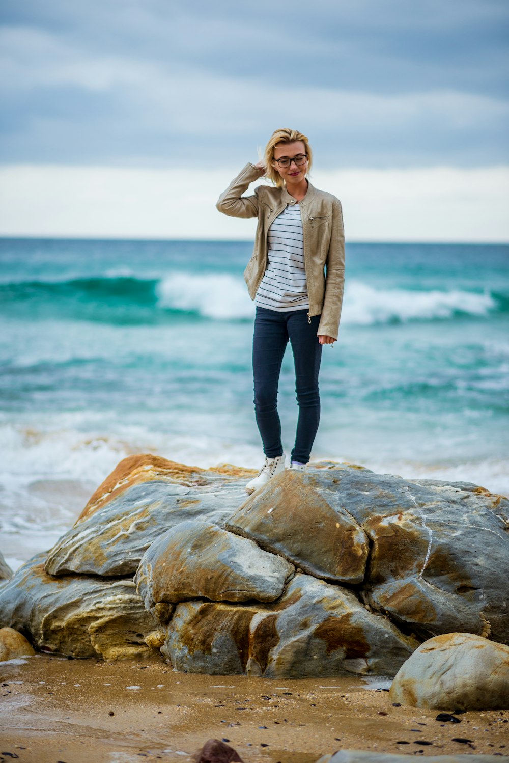 a woman standing on top of a rock near the ocean