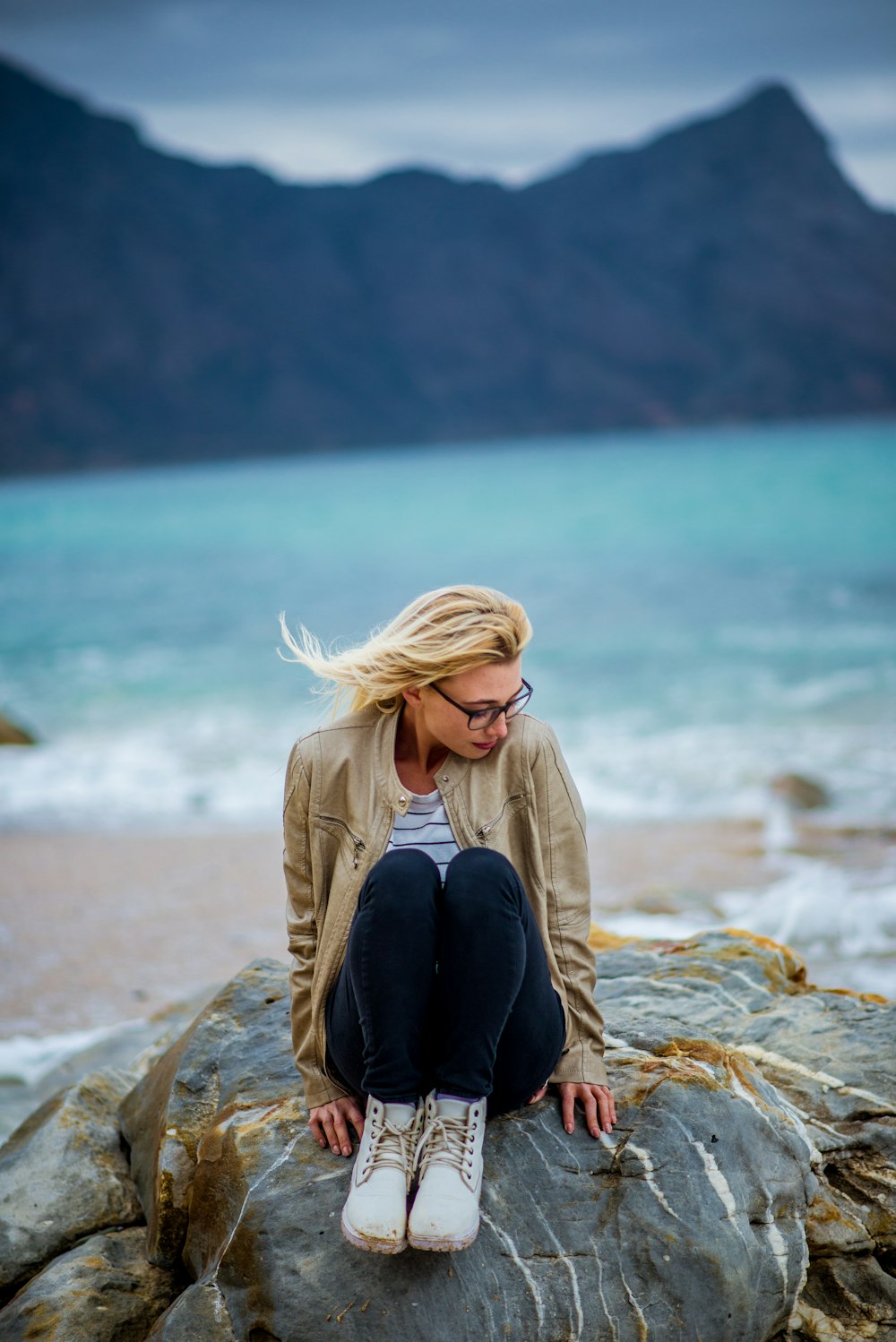 Una mujer sentada en la cima de una roca cerca del océano