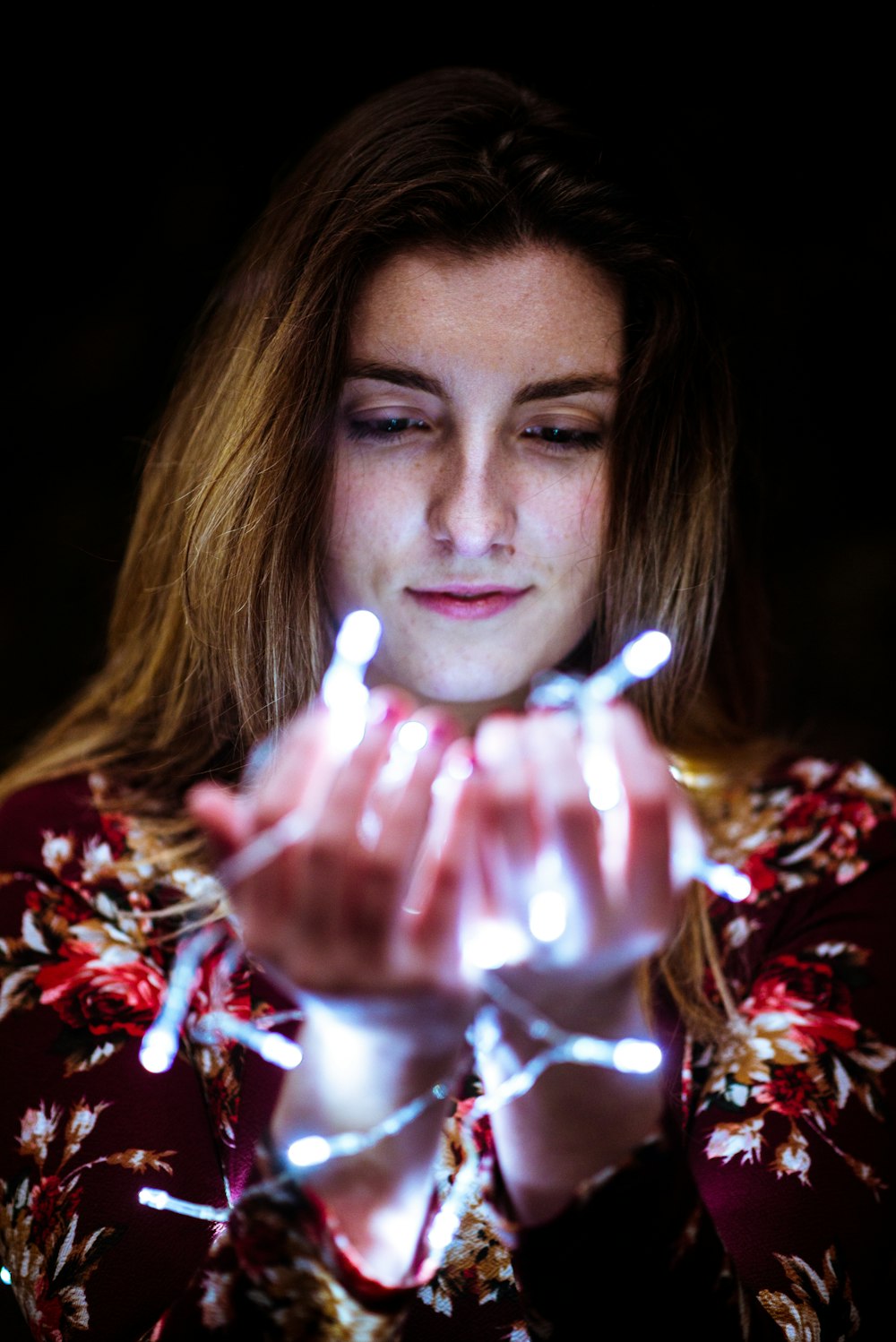 a woman holding a lit up hand in front of her face