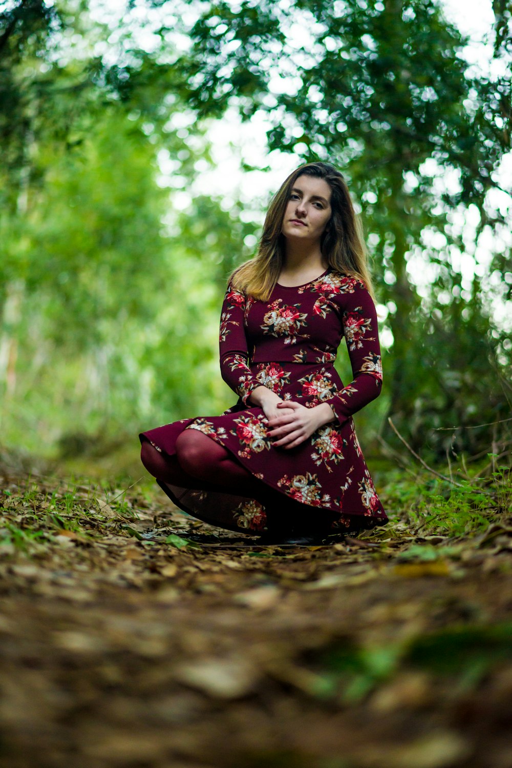 a woman sitting on the ground in a forest