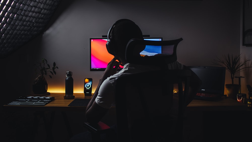 uma pessoa usando fones de ouvido sentada na frente de um computador