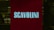 A red illuminated sign with the word 'SCAVOLINI' in bold white letters is positioned in front of what appears to be an interior setting, possibly a showroom or store. The background is dark, with some indistinct details, suggesting a dimly lit environment.