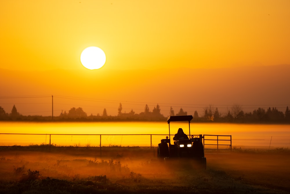 Eine Person, die bei Sonnenuntergang einen Traktor auf einem Feld fährt