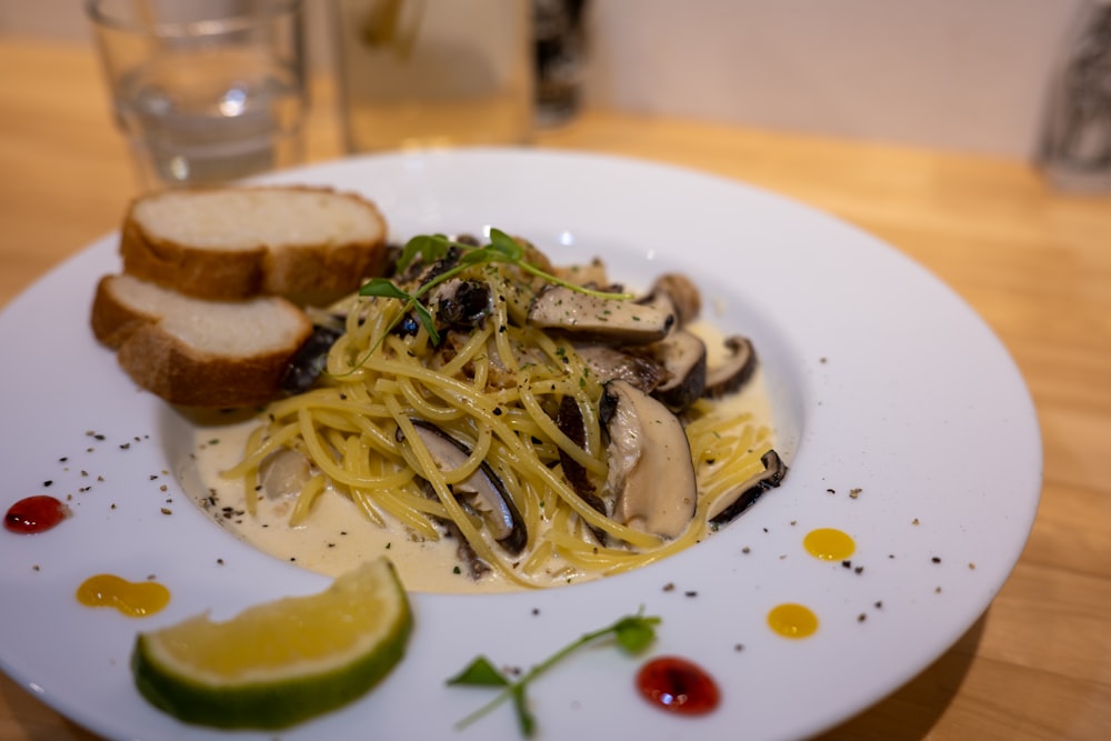 a plate of spaghetti with mushrooms and bread