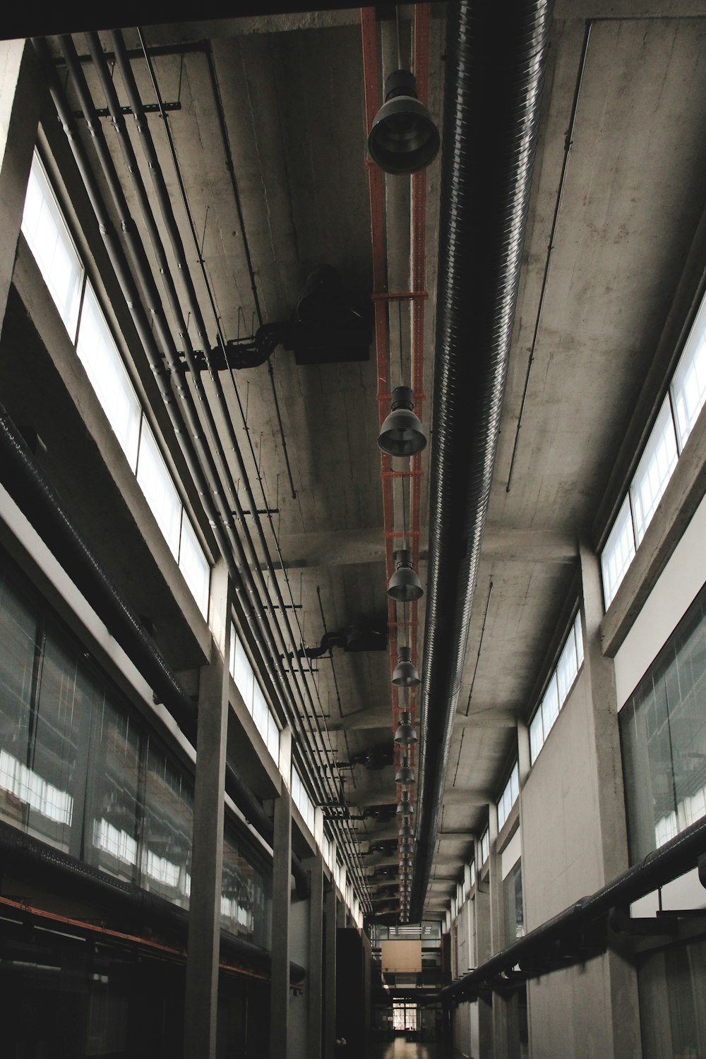 a long hallway with exposed pipes and windows