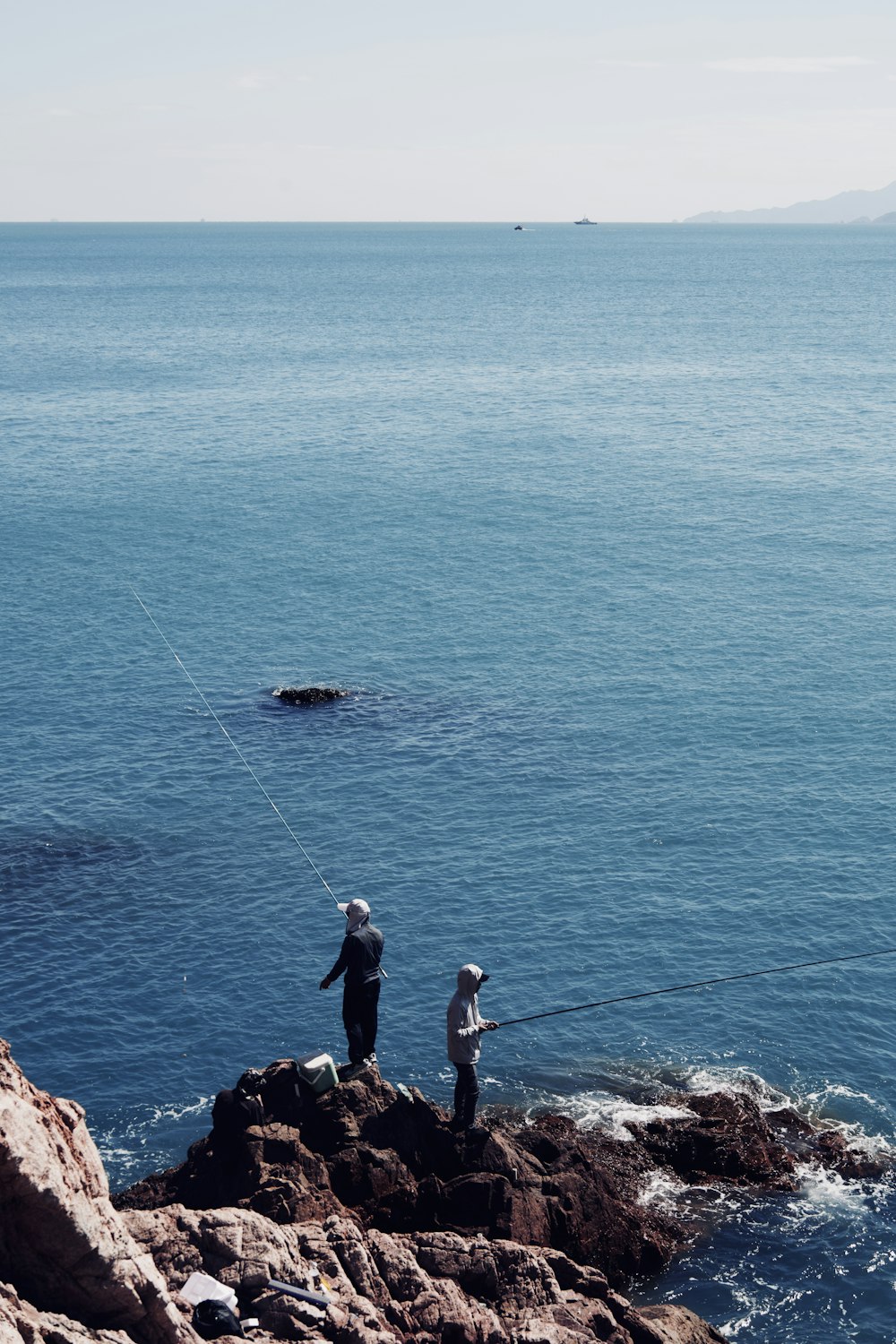 a couple of people standing on top of a rocky shore
