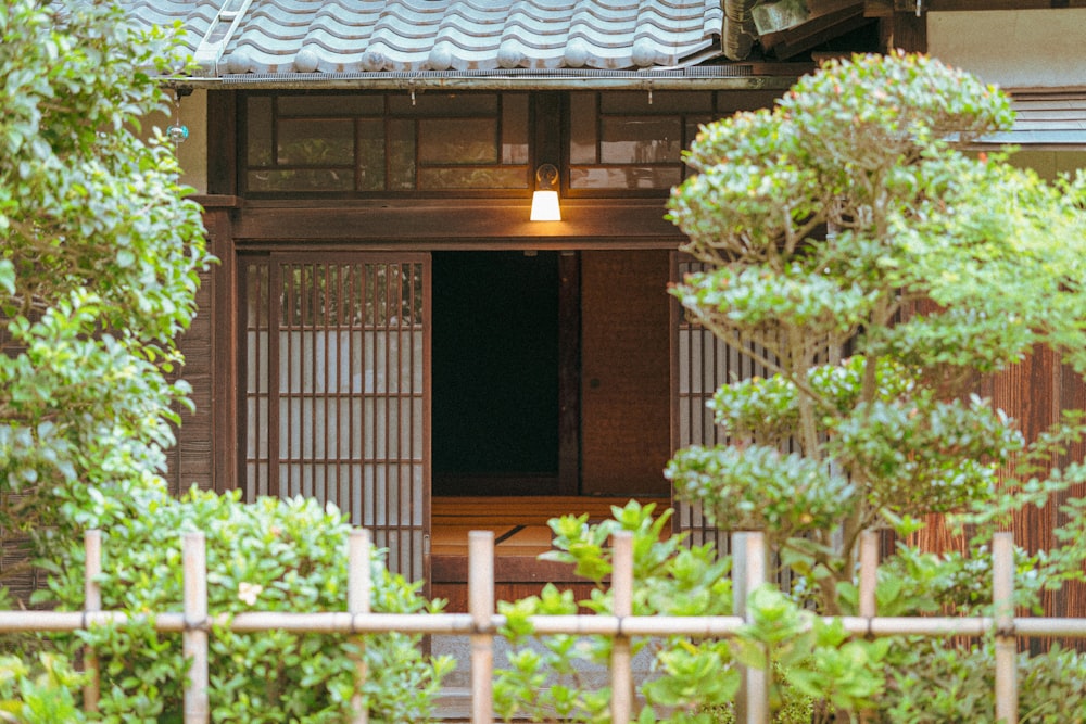 a small wooden building with a gate and trees in front of it