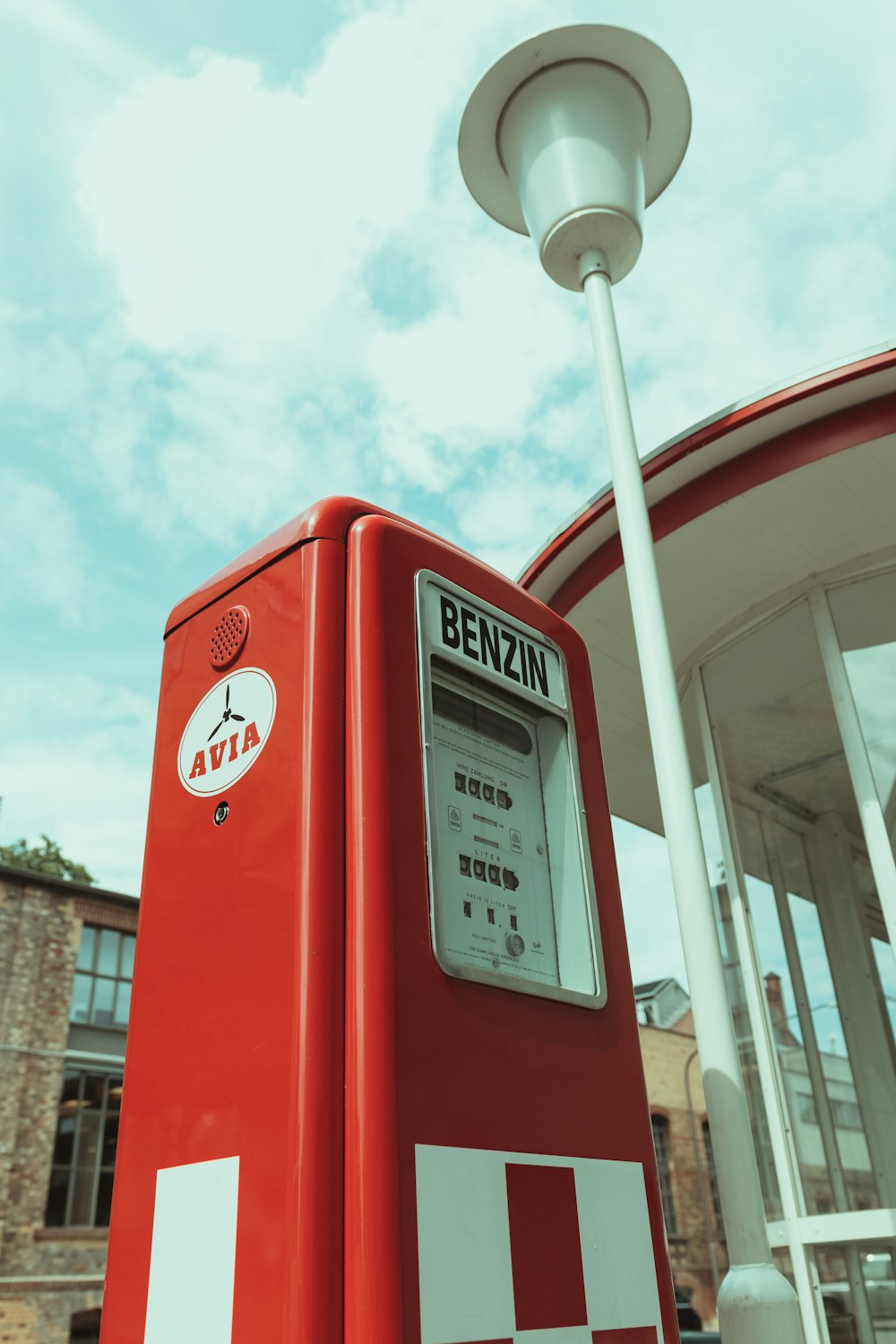 a red and white gas pump next to a building