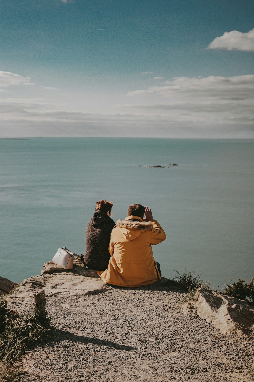 Un couple de personnes assises au sommet d’une falaise