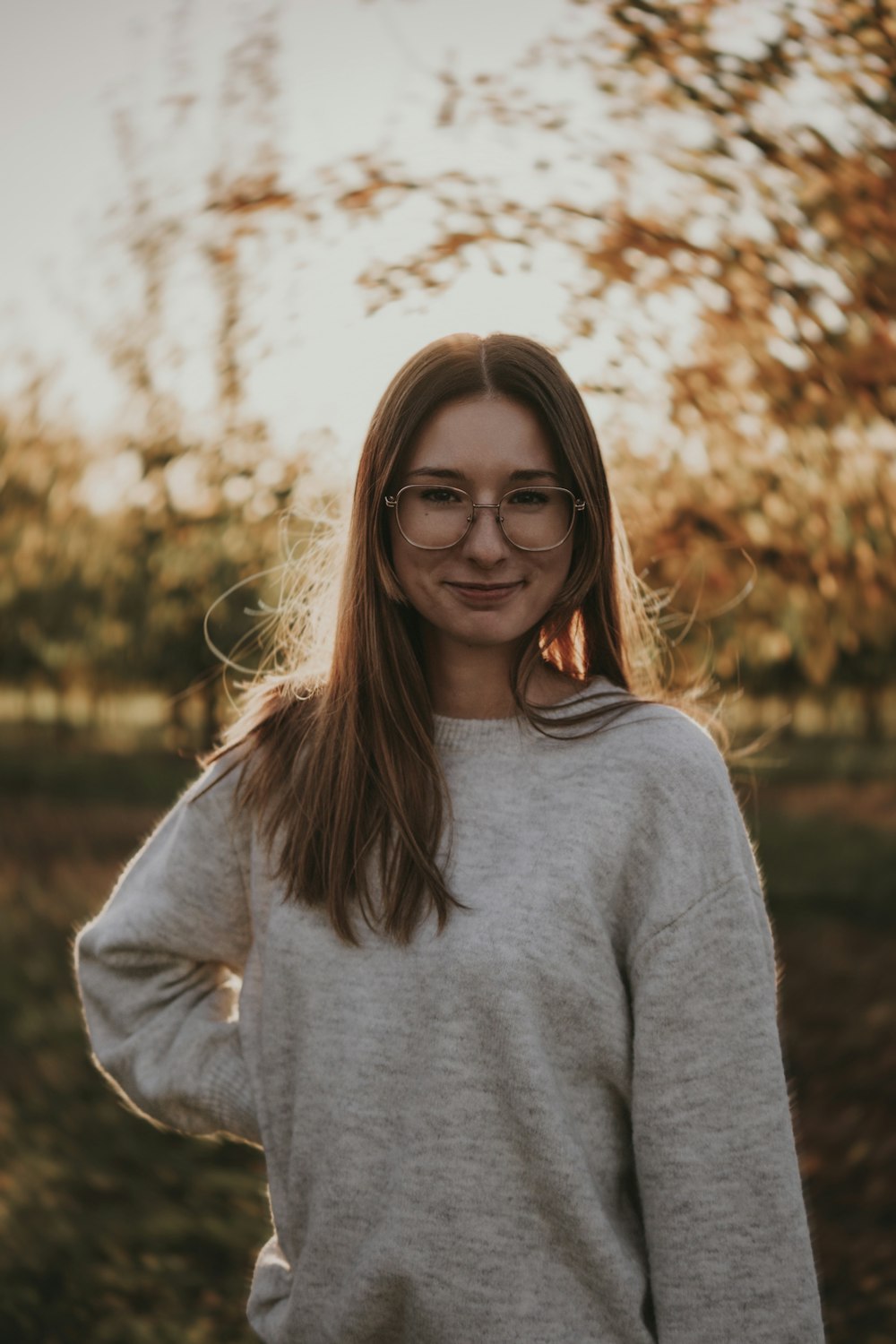 a woman wearing glasses standing in front of a tree