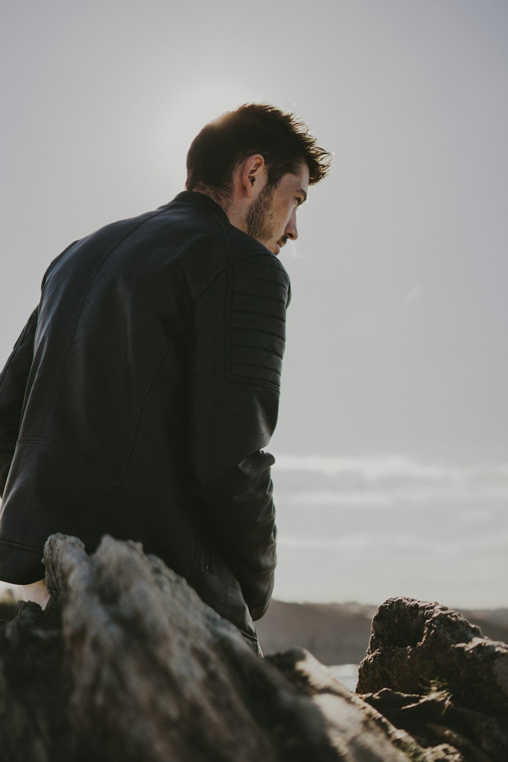 a man sitting on top of a rock near the ocean