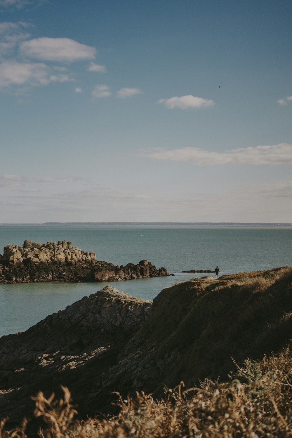 a couple of people standing on top of a hill next to a body of water