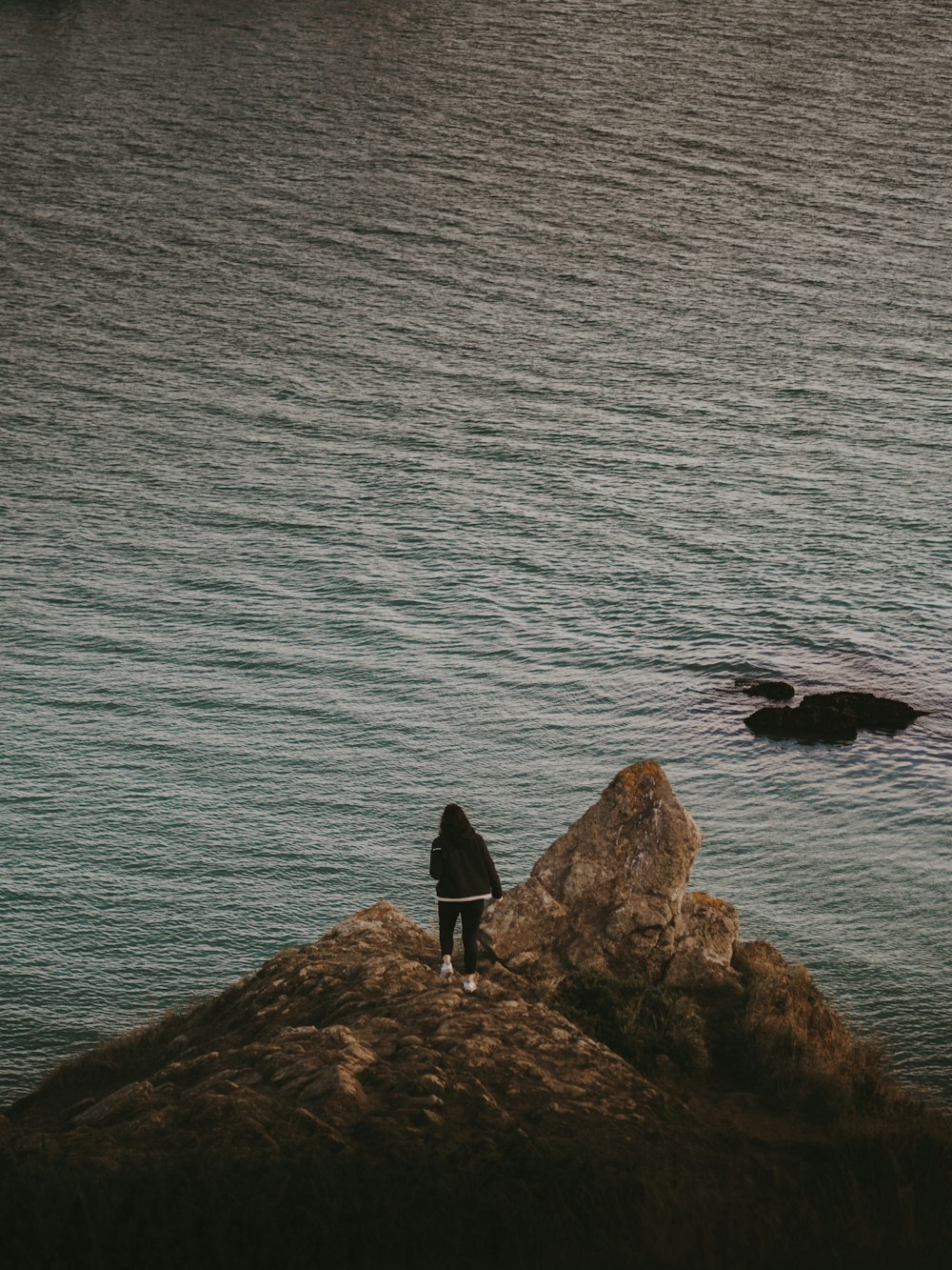 a person standing on top of a rock near the ocean