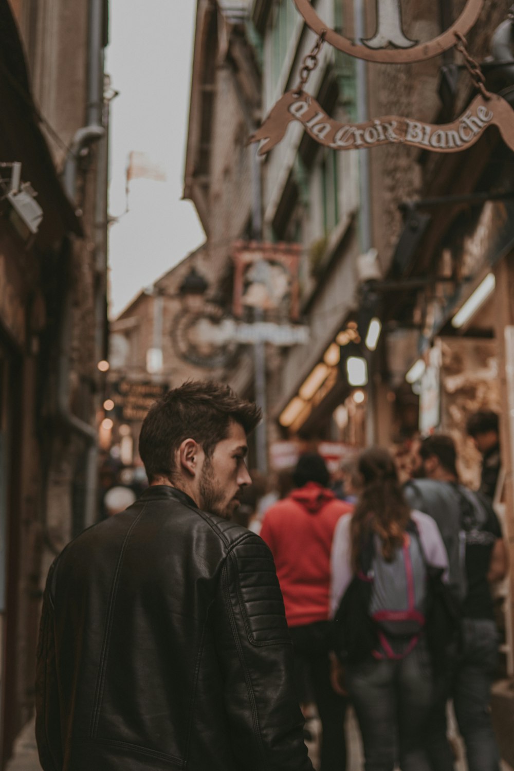 a man in a leather jacket walking down a street