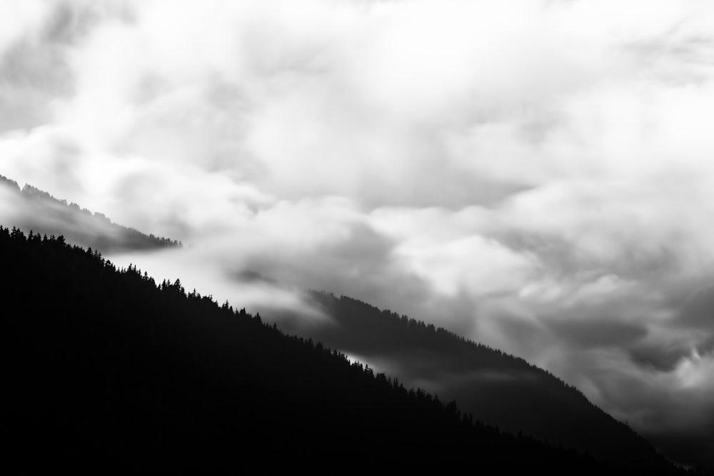 a black and white photo of a mountain covered in clouds