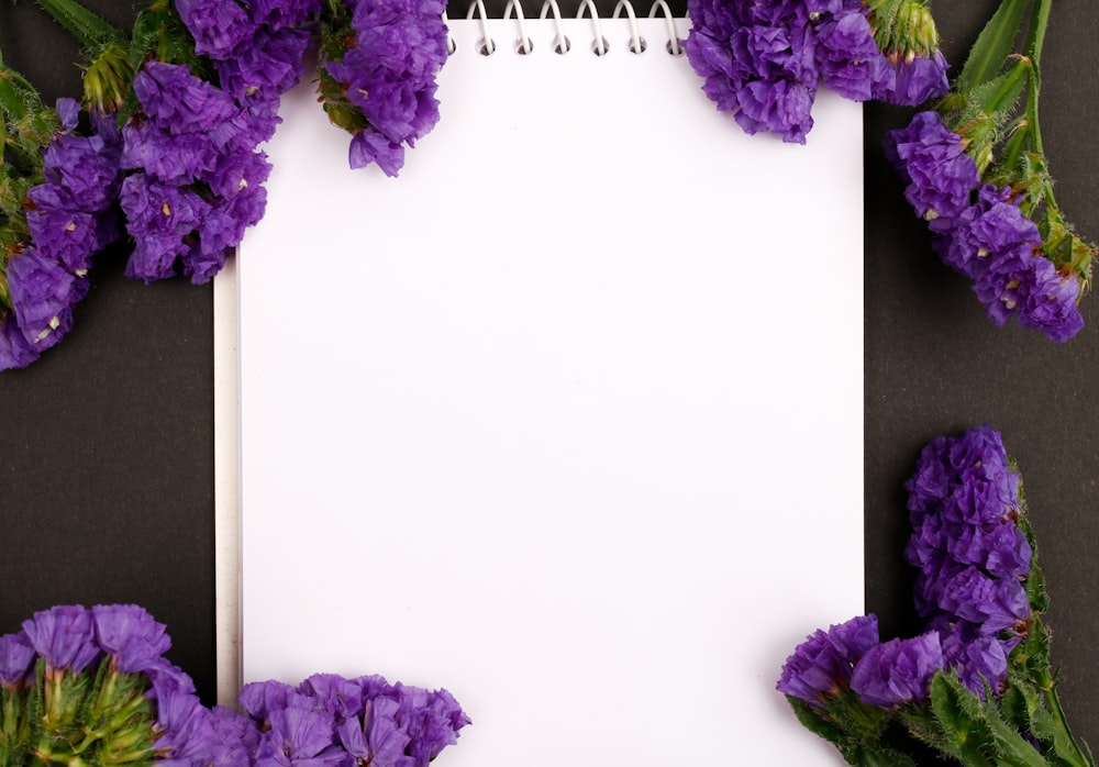 a notepad with purple flowers surrounding it