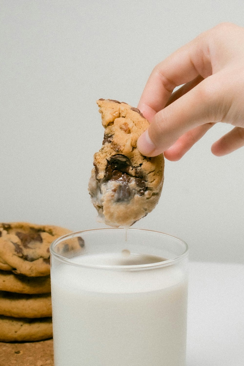 a person dipping a cookie into a glass of milk