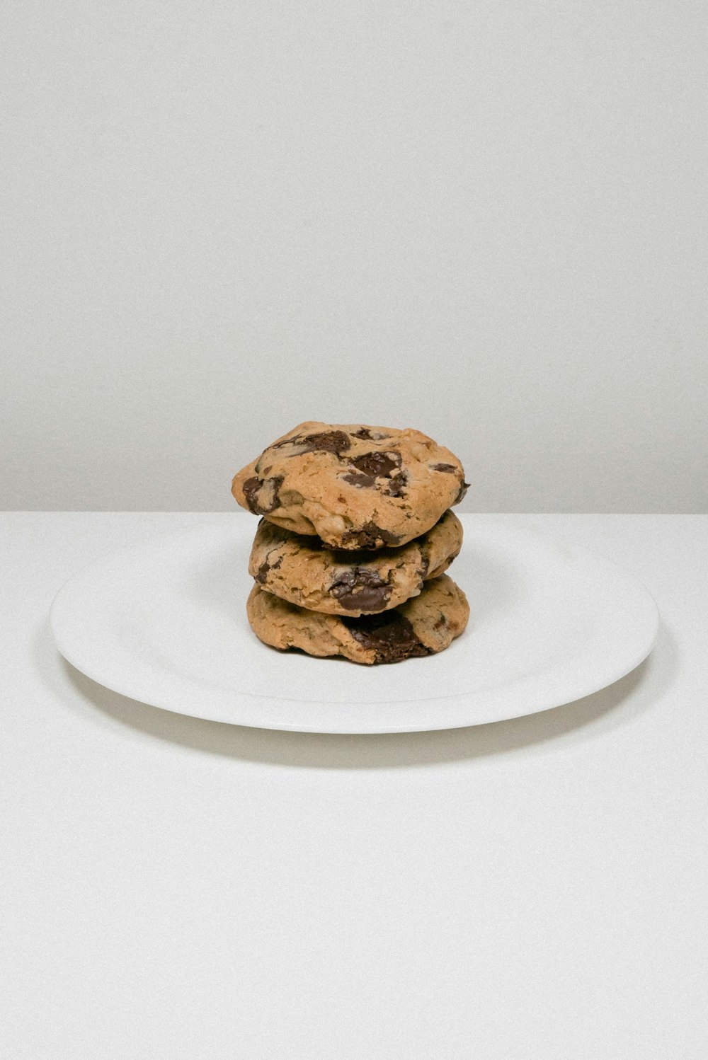 a stack of chocolate chip cookies on a white plate