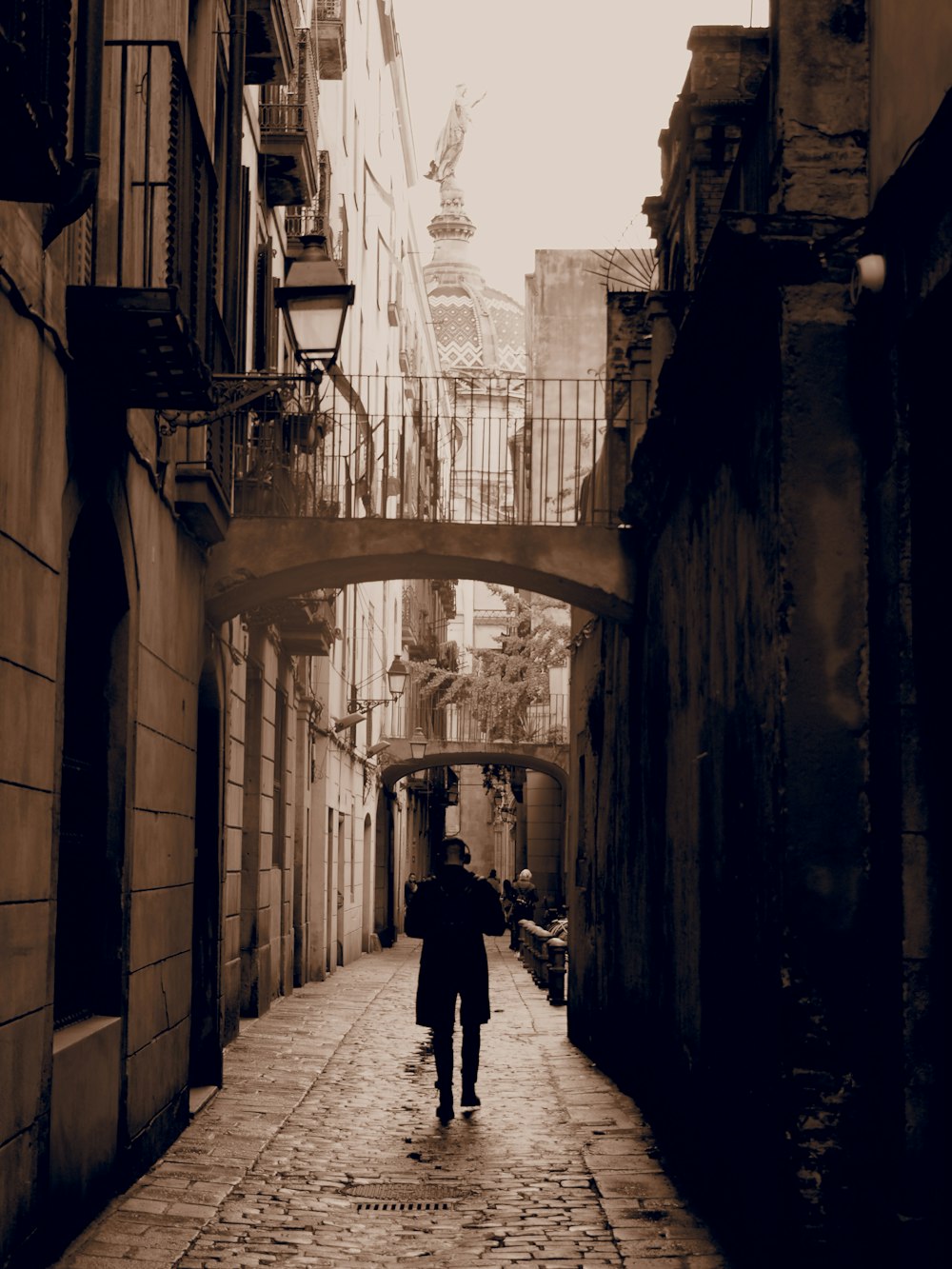 a couple of people walking down a street under a bridge