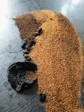 Golden cinnamon powder spilling gently onto a dark terracotta surface.