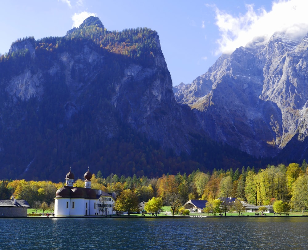 a church on the shore of a lake with mountains in the background