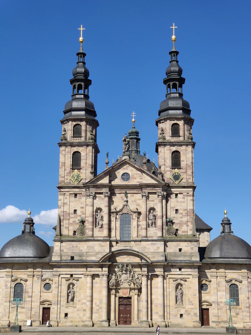 Large, two-story church with steeple and domes, stone construction and intricate carvings visible