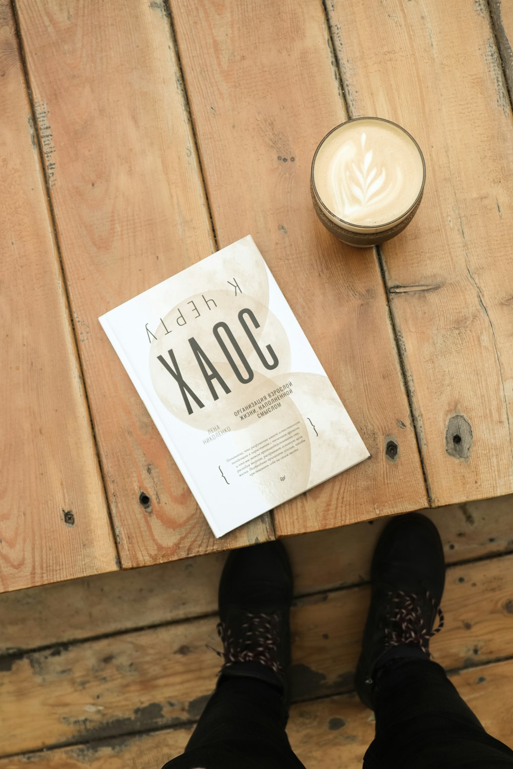 a book sitting on top of a wooden table next to a cup of coffee