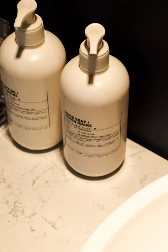 Close-up of a sleek stone kitchen soap dispenser on a marble countertop with a soft natural light.