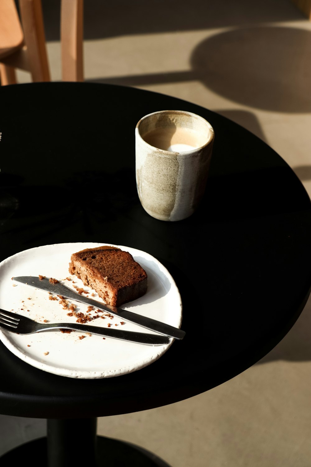 a plate with a piece of cake on it next to a cup of coffee