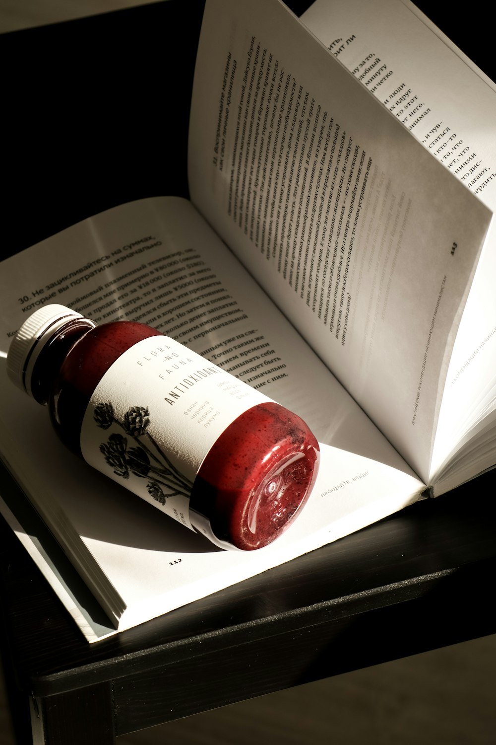 an open book with a jar of liquid on top of it