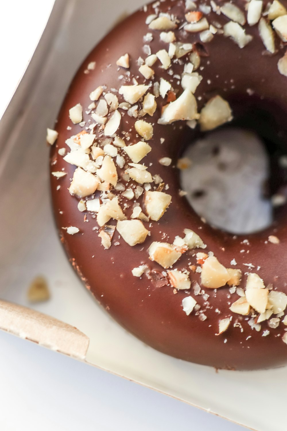 a chocolate donut with nuts and a bite taken out of it