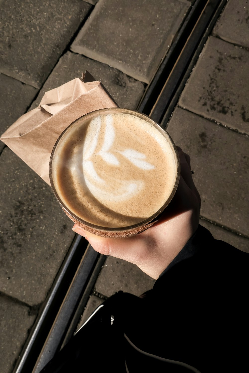 a person holding a paper bag with a latte in it