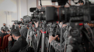 a large group of people in a room with cameras