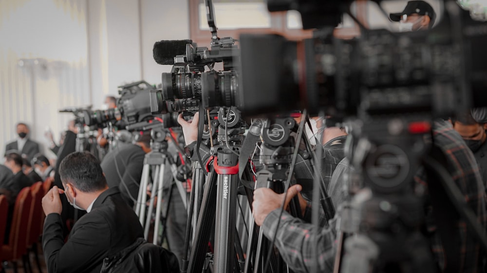 a large group of people in a room with cameras