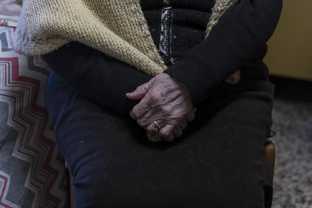 a woman sitting on a chair holding her hands together