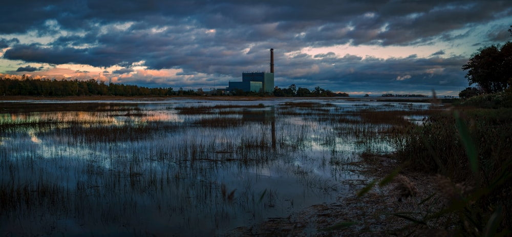 a body of water with a factory in the background