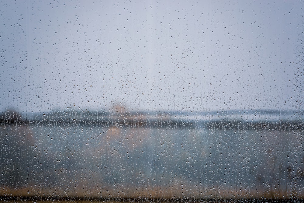 una vista di uno specchio d'acqua attraverso una finestra coperta dalla pioggia