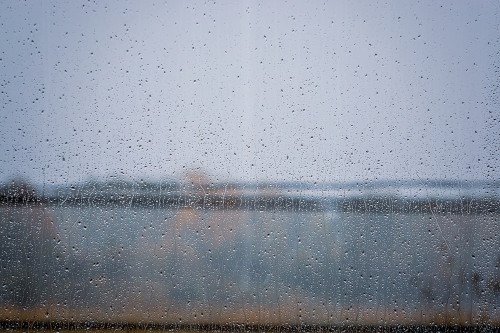 a view of a body of water through a rain covered window