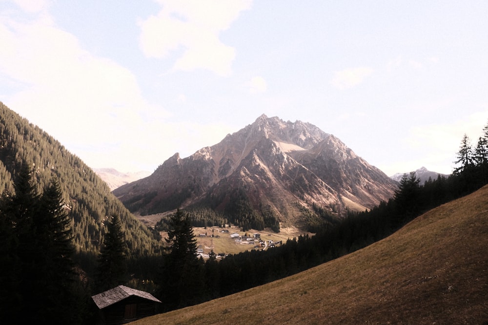 a view of a mountain range with a cabin in the foreground
