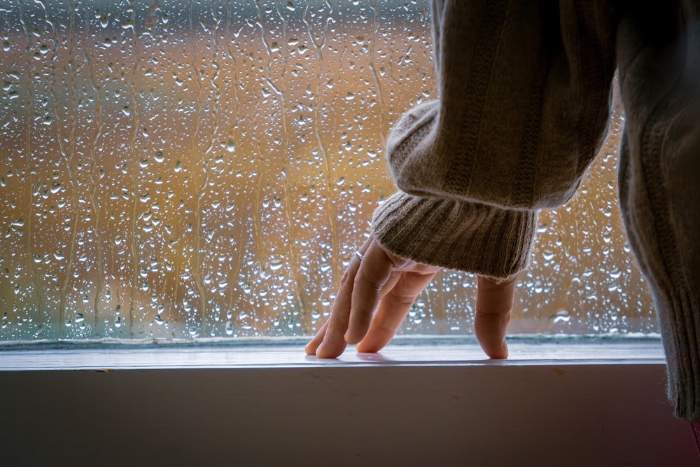 a person standing on a window sill in the rain
