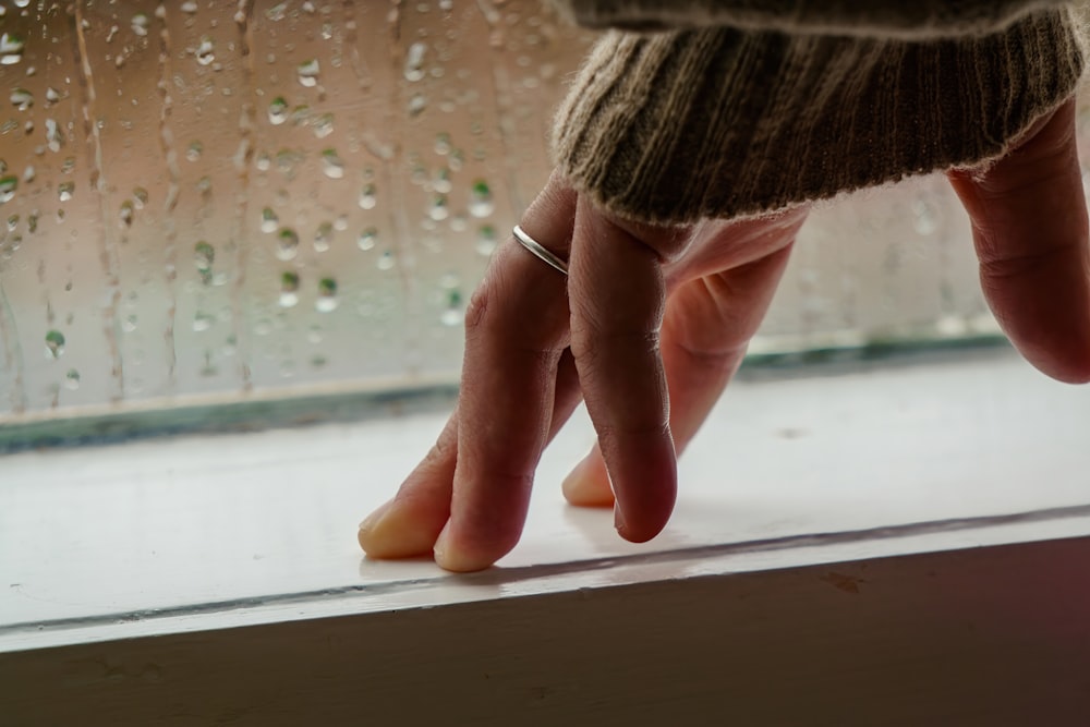 a person reaching for something on a window sill