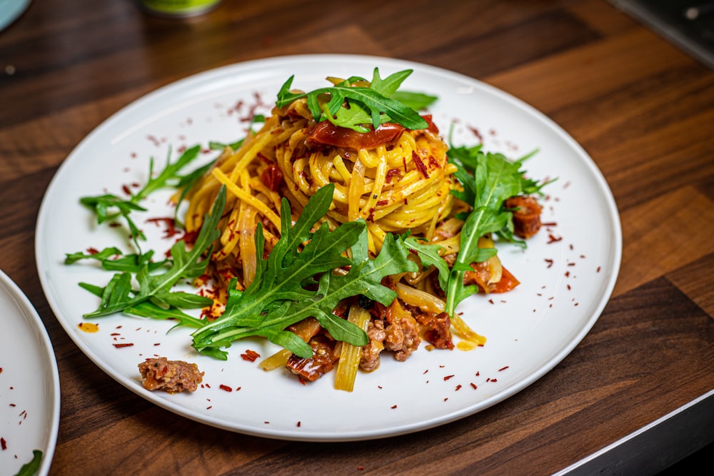 a white plate topped with pasta and greens