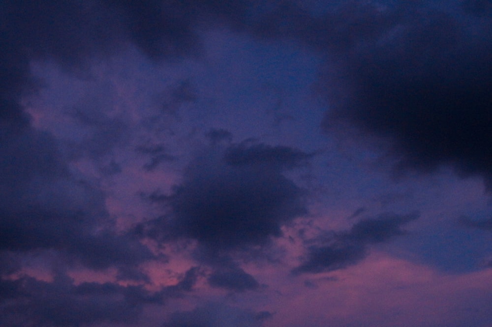 a plane flying through a cloudy sky at dusk